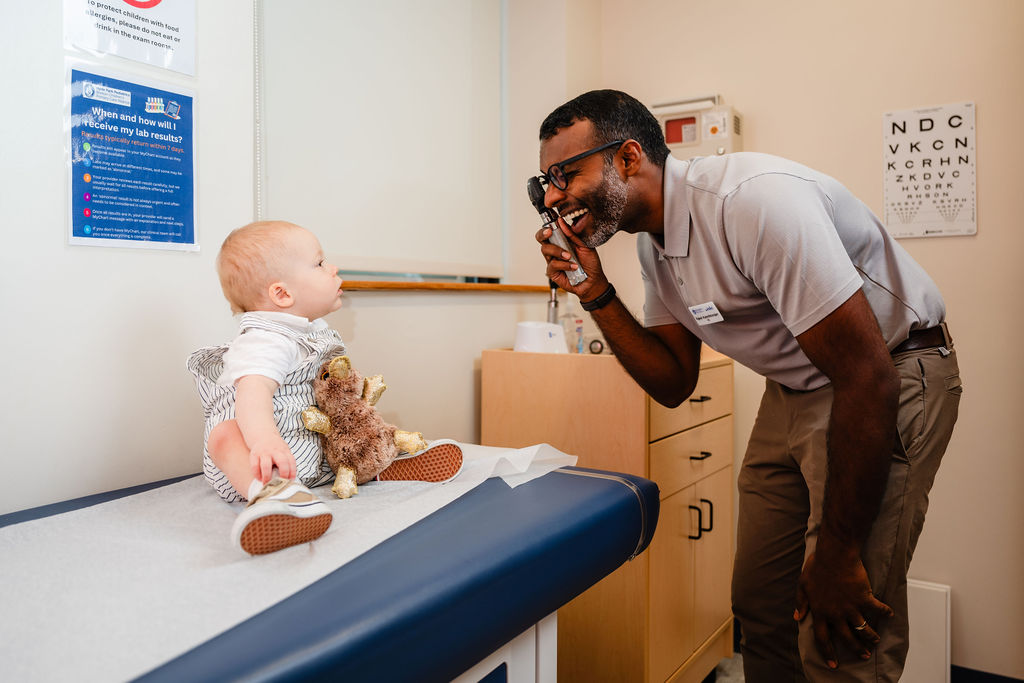 a pediatrician using a light to look into a young infants eyes