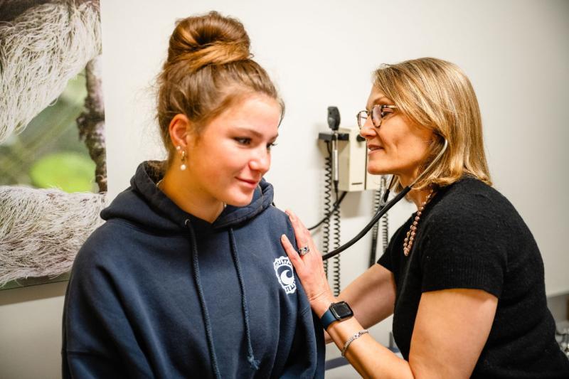 a pediatrician examining a teen girl