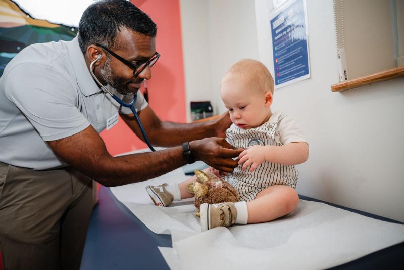 a pediatrician using a stethoscope on a young infant child